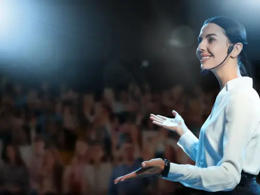 Oratrice sorridente sul palco, con microfono, che parla a un pubblico. Nonostante l'ansia, non riesco a parlare in modo fluido, ma cerco di comunicare.