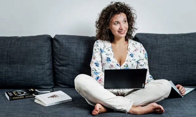 Donna con laptop e libri sul divano, esplora quali lavori si possono fare da casa.