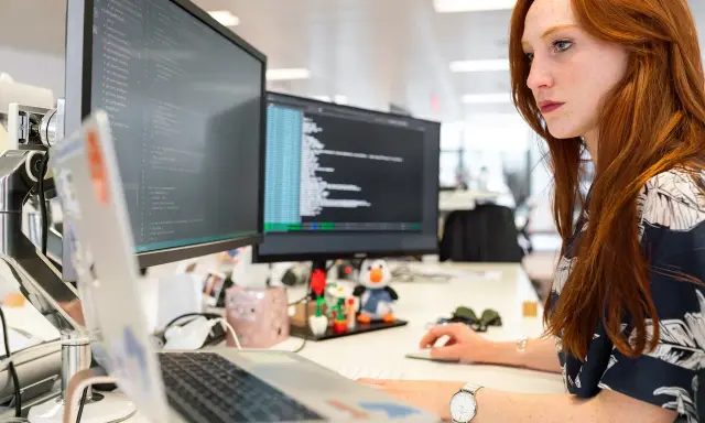 Donna con capelli rossi lavora al computer, analizzando codice. Un ingegnere gestionale cosa fa? Ottimizza processi e sistemi, proprio come lei con i dati.