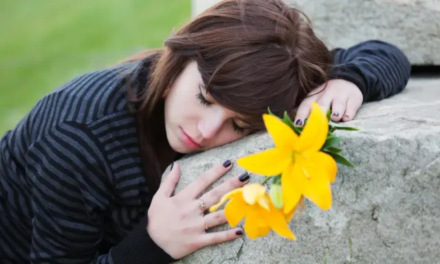 Ragazza con fiore giallo, triste, forse in attesa di un permesso per lutto suocero.