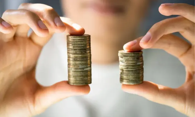 Due pile di monete, una più alta dell'altra, simboleggiano la differenza tra stipendi. Il **stipendio medio Lussemburgo** potrebbe essere rappresentato dalla pila più alta.