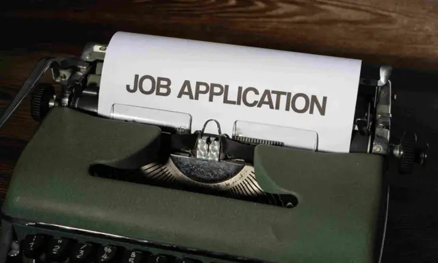 Macchina da scrivere verde con foglio "JOB APPLICATION". Una guida per chi vuole capire come trovare lavoro senza esperienza.
