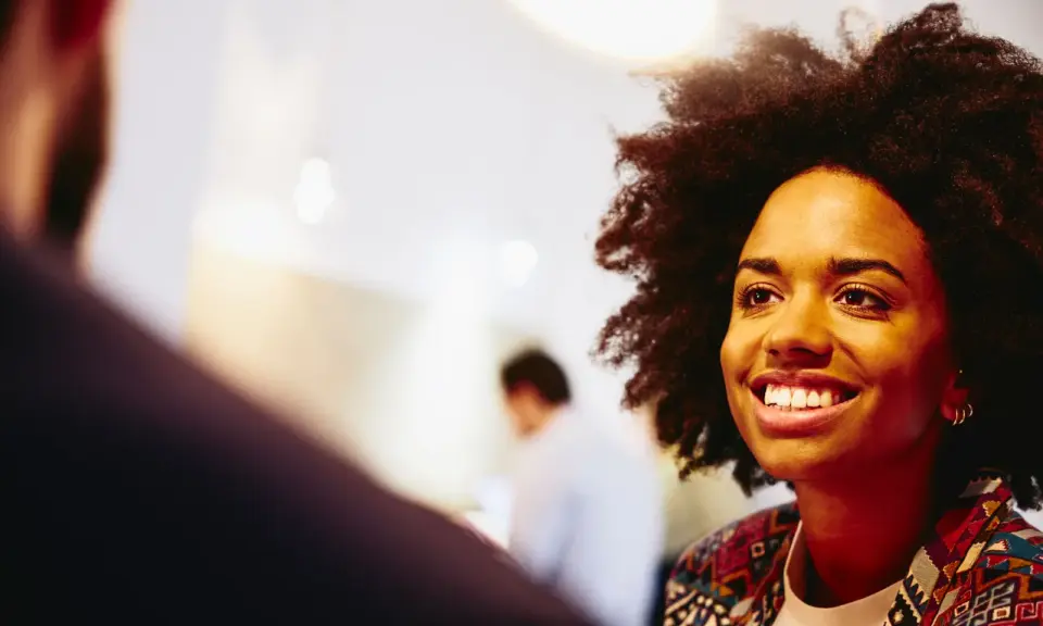Donna sorridente in primo piano, discute idee per capire che lavoro fare a 40 anni senza esperienza.
