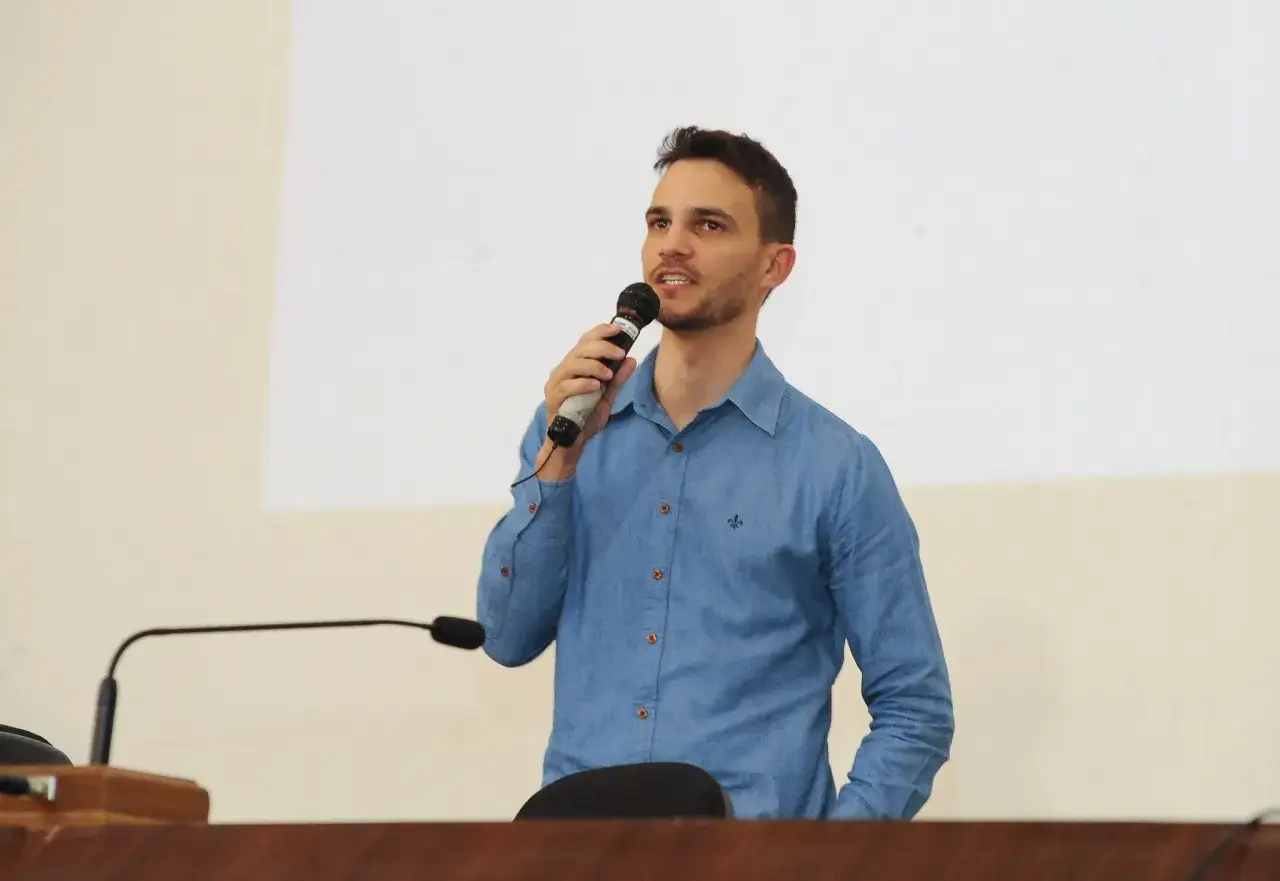 Uomo con camicia blu tiene un microfono, pronto per i suoi discorsi da fare.