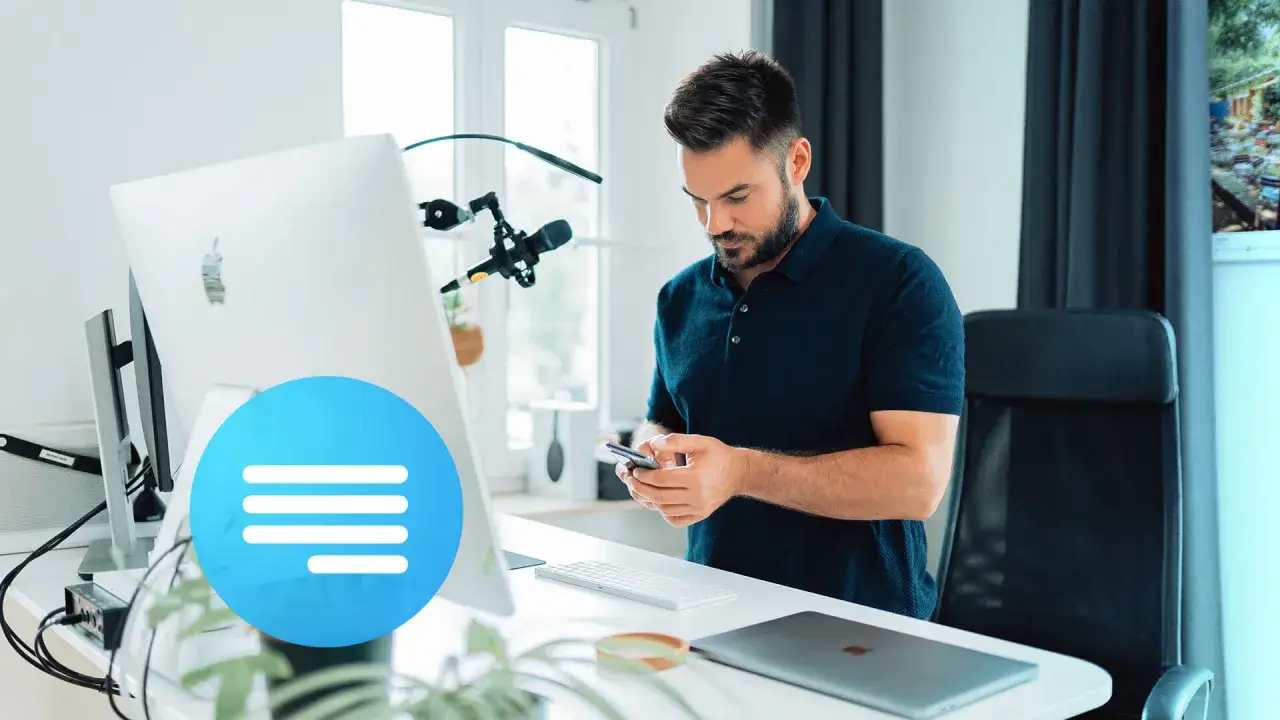 Un creator digitale al lavoro, concentrato sul suo smartphone, con un setup da ufficio moderno e un microfono pronto per la creazione di contenuti.