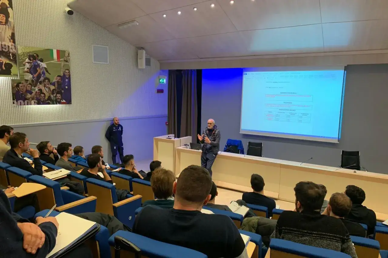 Un relatore spiega dati su un proiettore a un pubblico interessato, un'opportunit&agrave; per chi vuole lavorare nel calcio.