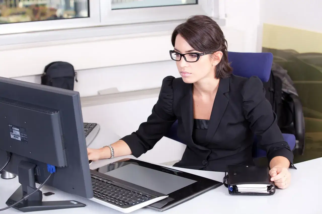 Donna con occhiali lavora al computer, una segretaria part time mattina, concentrata sui suoi compiti.