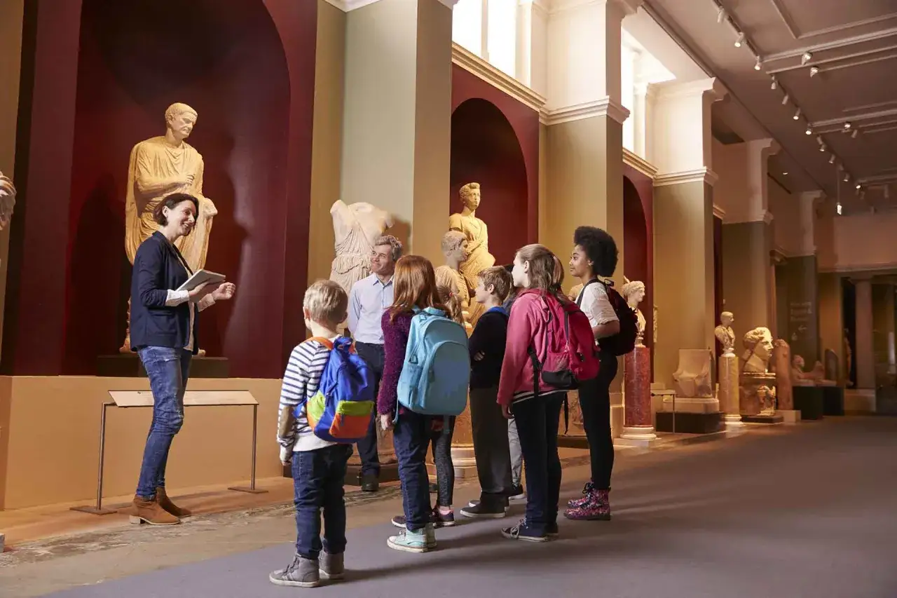Guida turistica che illustra statue antiche a un gruppo di bambini. Un'ottima giornata per lavorare in un museo e condividere la storia.