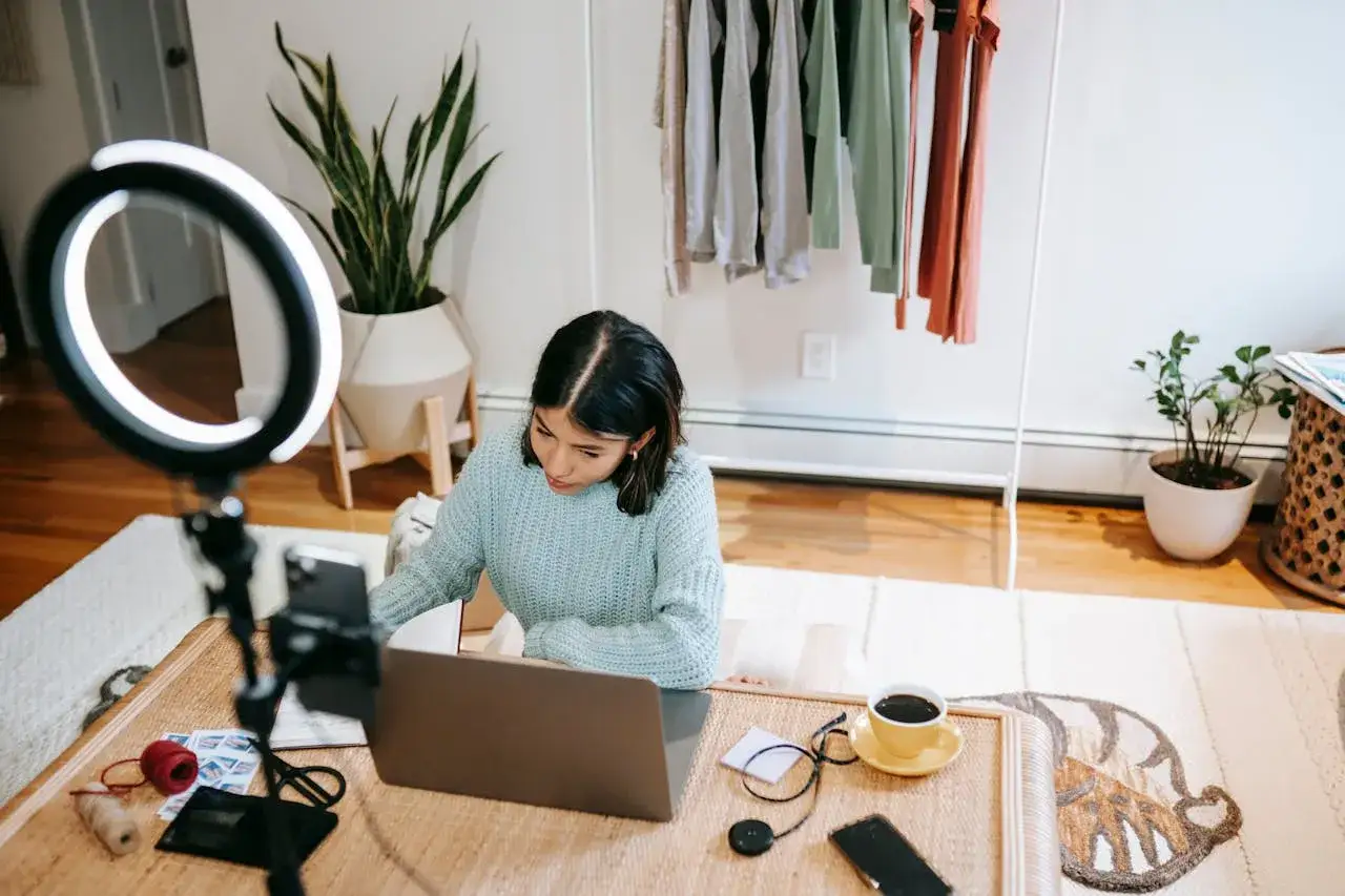 Una content creator prepara il suo set con luci e laptop. Cosa fa? Crea contenuti per il web, mostrando la sua passione per la moda e il fai-da-te.