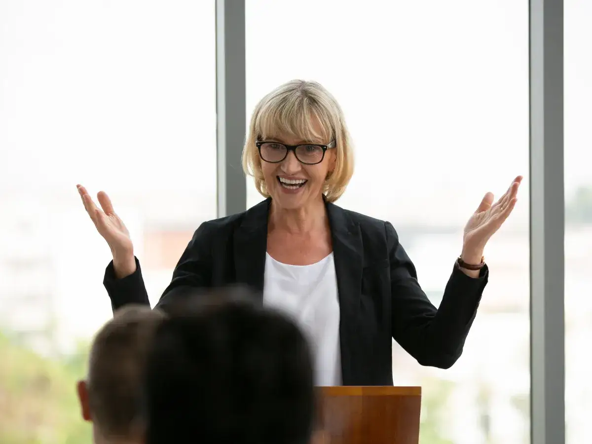 Donna sorridente con occhiali, giacca nera, parla con entusiasmo. Non riesco a parlare in modo fluido, ma lei ispira.