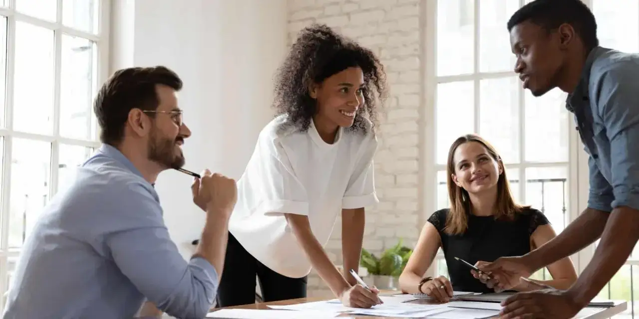 Donne e tecnologia in un team collaborativo. Un gruppo eterogeneo discute idee, con una donna al centro che scrive appunti, dimostrando leadership e innovazione.