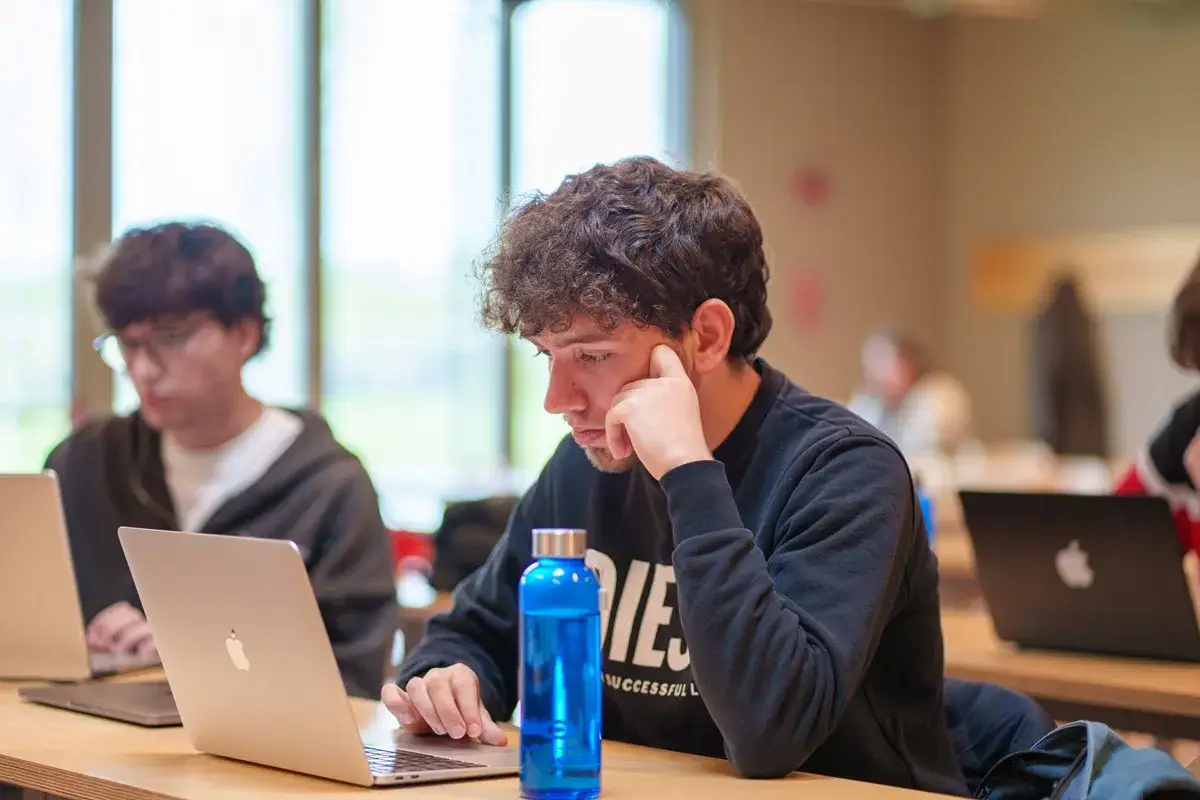 Giovane uomo concentrato al computer, forse studia per diventare business analyst e scoprire il suo futuro stipendio.
