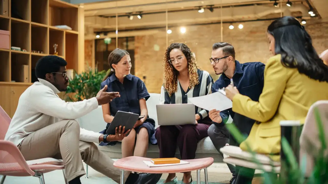 Un gruppo di professionisti discute animatamente, ognuno con un'idea da condividere, prima di parlare.