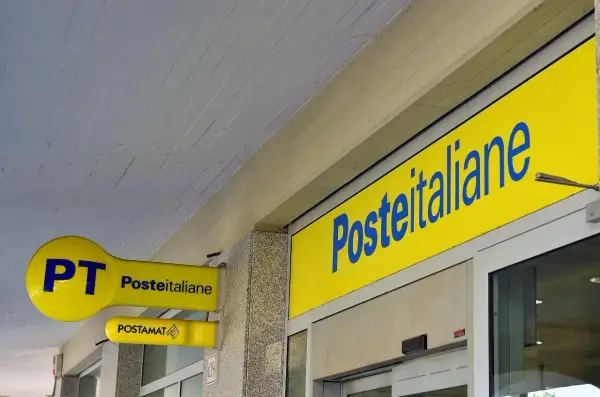Insegne gialle di Poste Italiane, con logo PT e Postamat. Un invito a partecipare al concorso Poste Italiane.